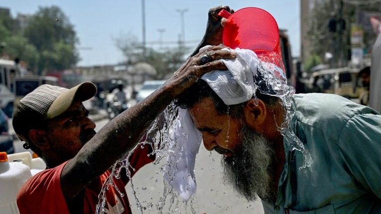 歩行者の頭に水を掛けるボランティア＝５日/Rizwan Tabassum/AFP/Getty Images