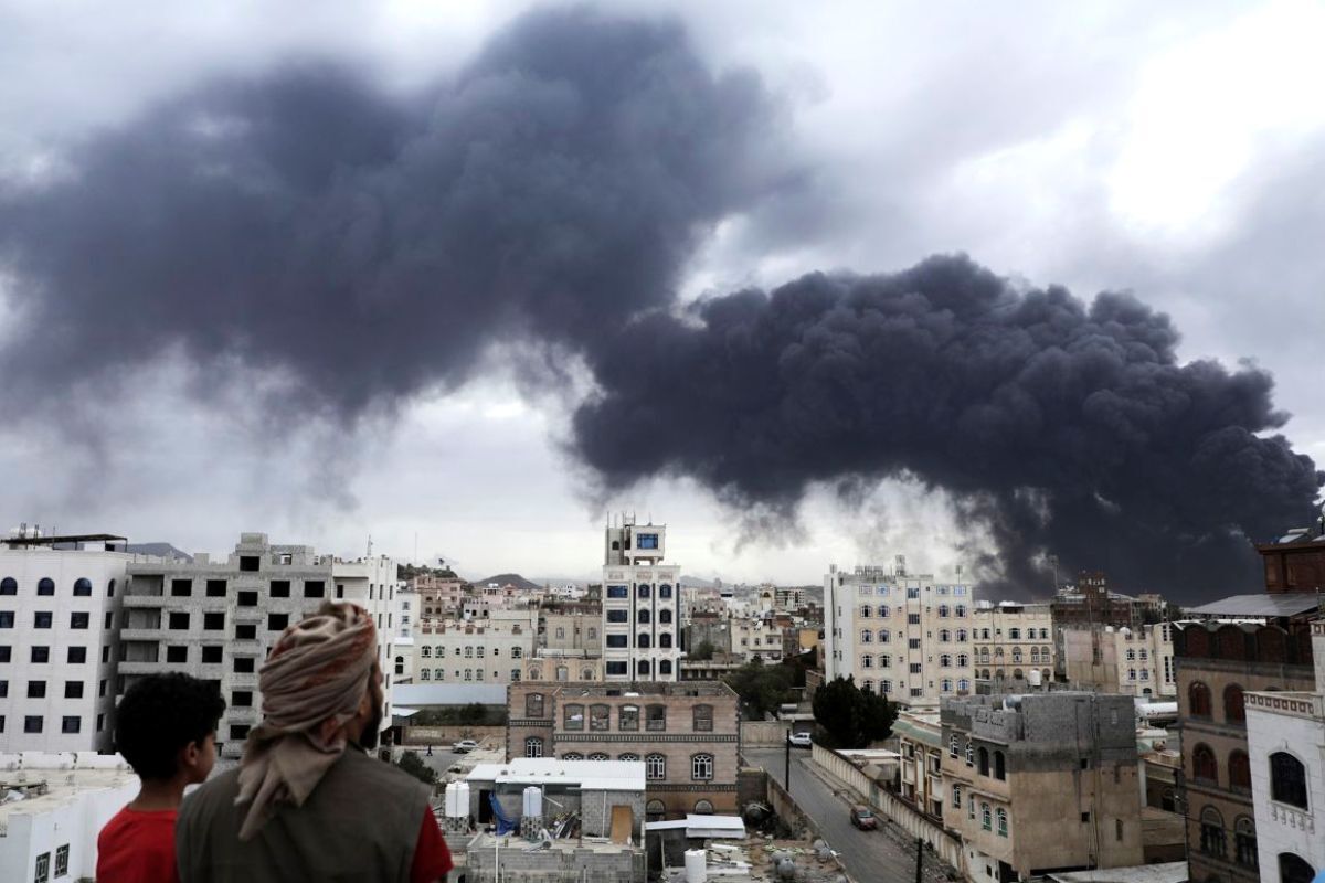 上空に立ち上る煙を見る人々=6日、イエメン首都サヌア/Osamah Abdulrahman/AP