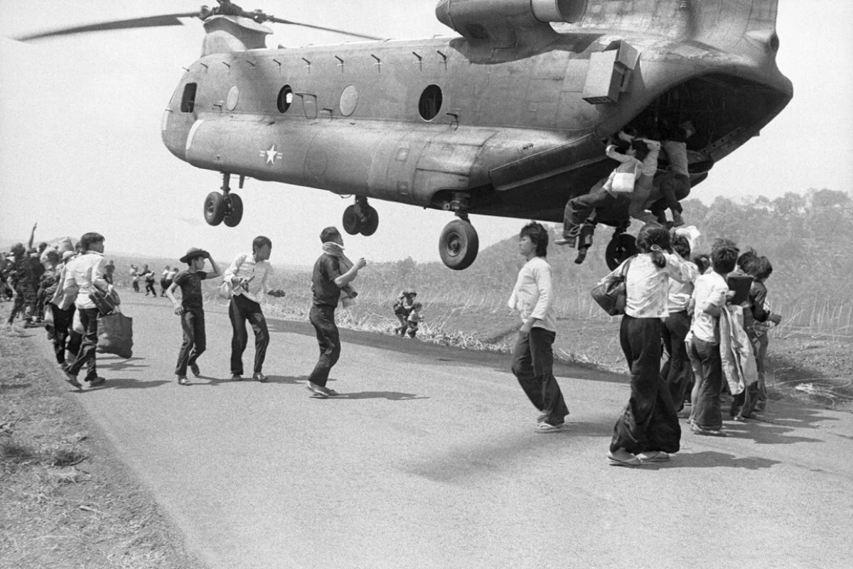 難民が物資投下後に離陸しようとするチヌークヘリにしがみつく様子＝１９７５年４月１４日