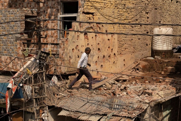 がれきのなかを移動する男性＝１０日/Adnan Abidi/Reuters