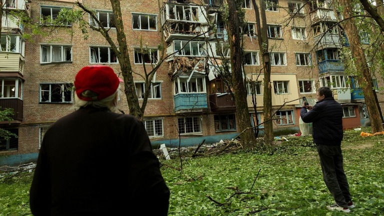 ロシアの攻撃で損傷した集合住宅を見る住民＝２４日/Thomas Peter/Reuters