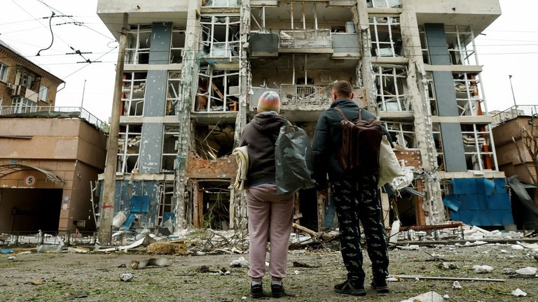 ロシア軍の無人機攻撃によって破壊された住宅を眺める住民＝２５日、ウクライナ首都キーウ/Thomas Peter/Reuters
