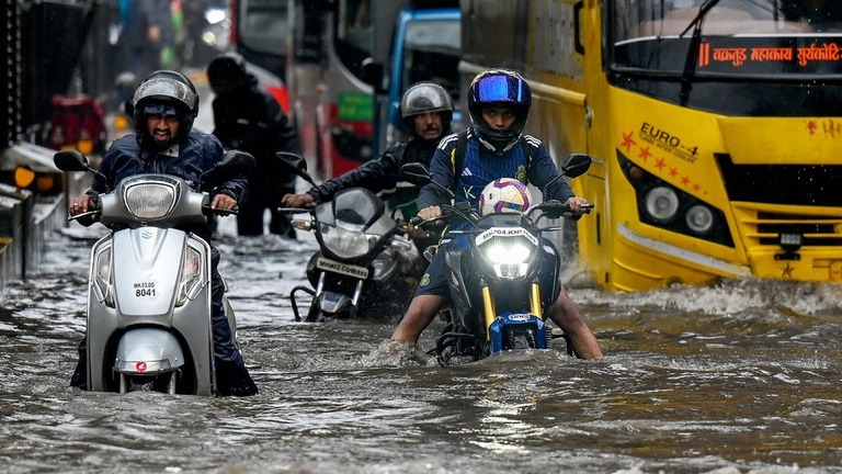 冠水した道路を移動するインドの人々＝２６日、インド・ムンバイ/Punit Paranjpe/AFP/Getty Images