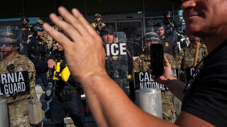ロサンゼルスでの抗議デモに対応する警察と州兵に携帯電話を向ける人物/Spencer Platt/Getty Images
