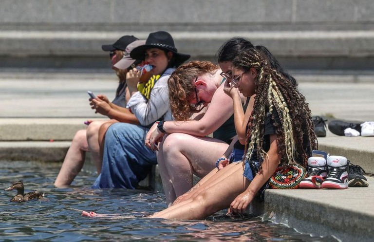 水の中に脚を入れて涼を取る人たち＝２４日、米首都ワシントン/Evelyn Hockstein/Reuters