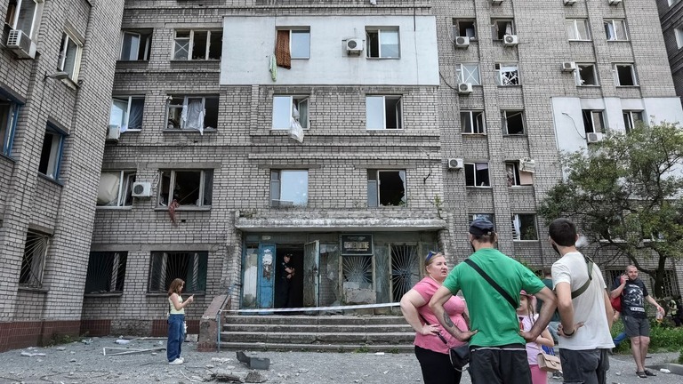 ロシア軍の空爆によって損傷した建物の前に集まる住民ら＝２４日、ウクライナ・ドニプロ/Mykola Synelnykov/Reuters