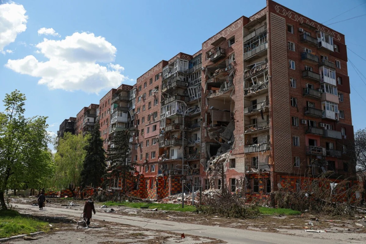ロシア軍の攻撃を受けた集合住宅のそばを歩く住民=4月23日、ポクロウスク/Nina Liashonok/Reuters
