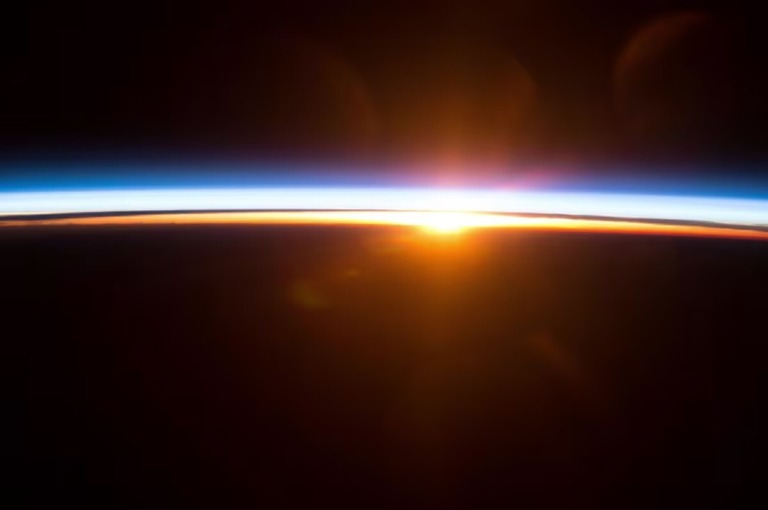太陽が地球の地平線の上に昇る様子。国際宇宙ステーションから見た光景/NASA
