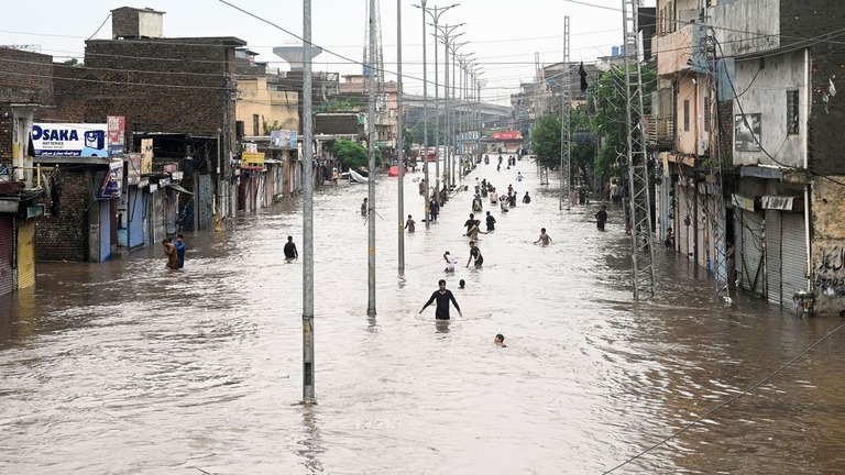 洪水が襲ったラワルピンディで、川のようになった道路を移動する人々/Anadolu/Getty Images
