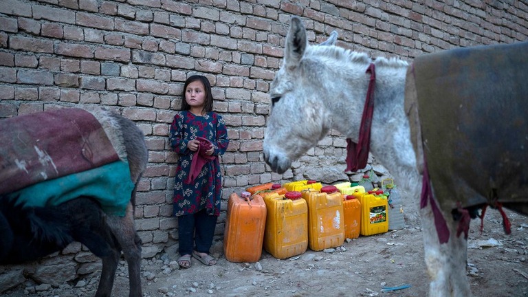 給水のための容器を用意して待機する少女＝２０２１年１１月、アフガニスタン首都カブール/Petros Giannakouris/AP