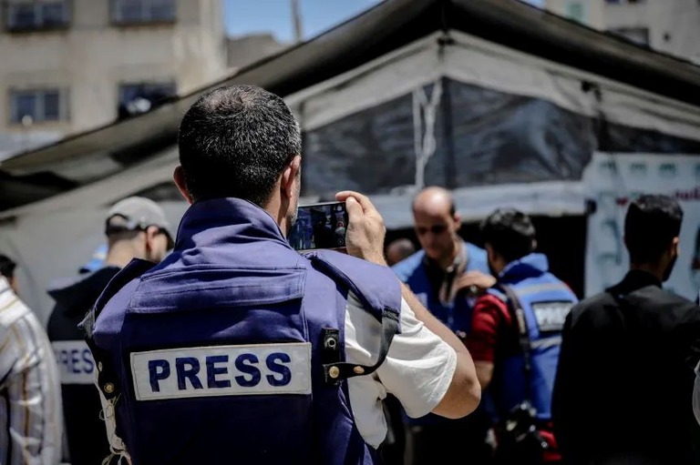 記者であることを示すベストを着用してガザを取材する男性/Saeed Jaras/AFP/Middle East Images/Getty Images