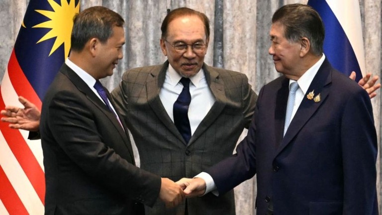 握手するカンボジアのフン・マネット首相（左）とタイのプームタム暫定首相（右）。中央はマレーシアのアンワル首相＝２８日/Mohd Rasfan/Pool/AFP via Getty Images