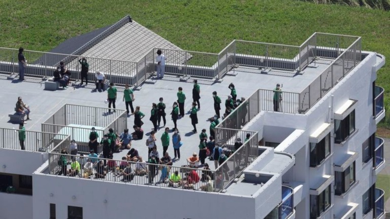 津波警報の発令後、建物の屋上に避難する人々＝３０日、大網白里市/Toshiyuki Kon/The Yomiuri Shimbun/AP