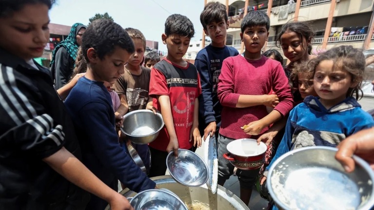 支援団体からの食事を受け取るパレスチナの子どもたち＝１日、パレスチナ自治区ガザ地区中部デイルアルバラ/Ramadan Abed/Reuters