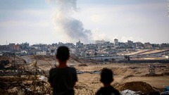 ガザ南部ラファへの空爆で立ち上る煙を眺める少年たち